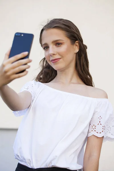 Hübsche junge brünette Frau macht Selfie auf dem Smartphone — Stockfoto