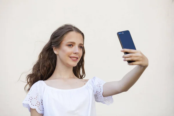 Hübsche junge brünette Frau macht Selfie auf dem Smartphone — Stockfoto