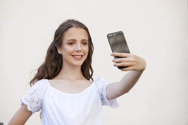 Hübsche junge brünette Frau macht Selfie auf dem Smartphone — Stockfoto