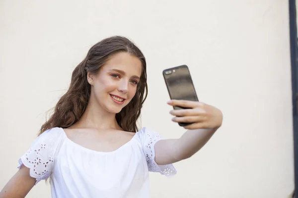 Hübsche junge brünette Frau macht Selfie auf dem Smartphone — Stockfoto