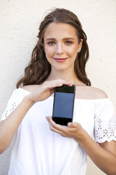 सुंदर लड़की अपने स्मार्टफ़ोन स्क्रीन दिखा रही है — स्टॉक फ़ोटो, इमेज
