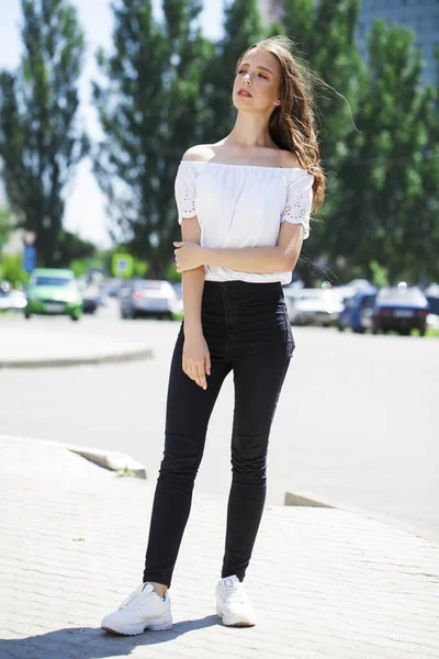 Joven hermosa morena mujer en jeans y blusa blanca caminando —  Fotos de Stock