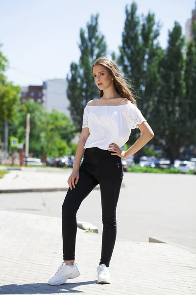 Young beautiful brunette woman in jeans and white blouse walking — Stock Photo, Image