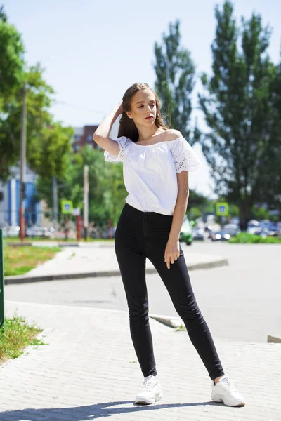 Jonge mooie brunette vrouw in jeans en witte blouse wandelen — Stockfoto