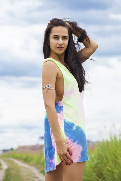 Young beautiful woman in colored tunic posing against the backgr — Stock Photo, Image