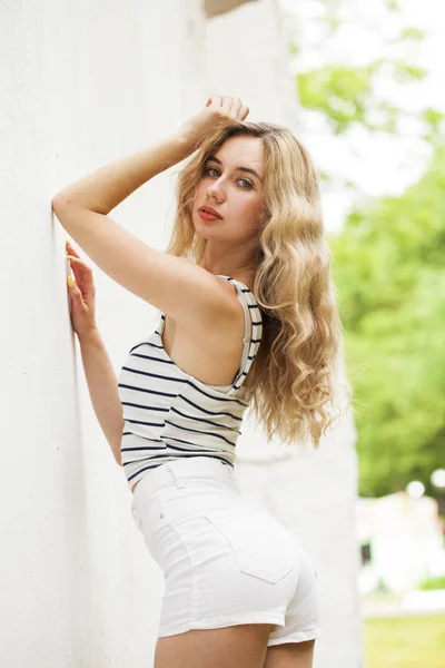 Retrato de una joven hermosa rubia en pantalones cortos blancos — Foto de Stock