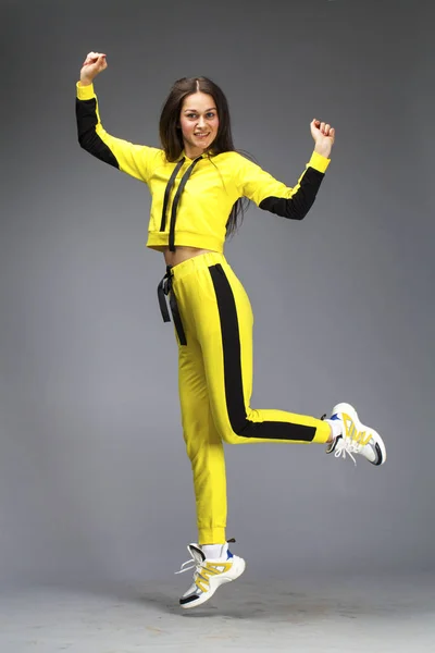 Porträtt av en ung vacker brunett kvinna i gul träningsoverall — Stockfoto