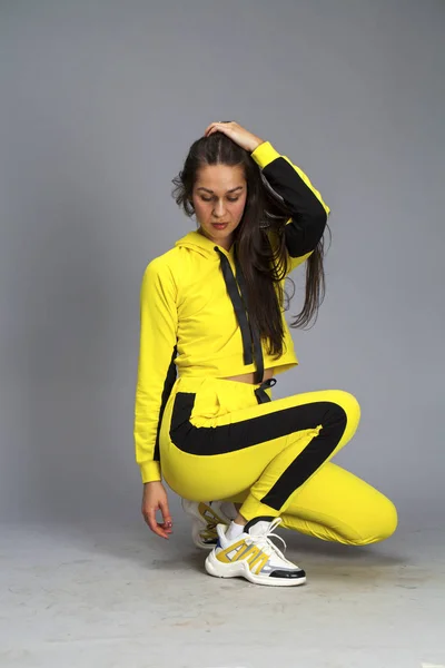 Portrait of a young beautiful brunette woman in yellow tracksuit — Stock Photo, Image