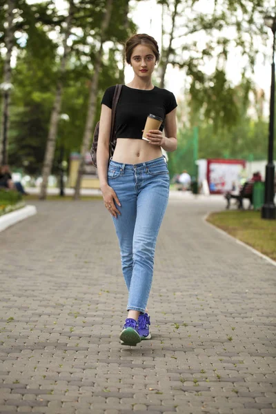 Junge schöne brünette Mädchen in Jeans und T-Shirt zu Fuß in su — Stockfoto