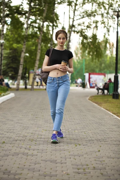 Joven chica morena hermosa en jeans y camiseta caminando en su —  Fotos de Stock