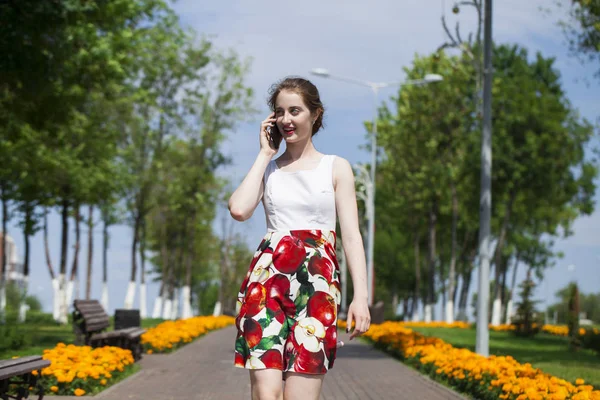 Portrét šťastné mladé Brunetky v šatech s telefonem, venkovní letní ulice — Stock fotografie