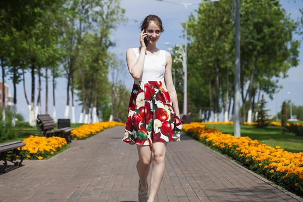 Porträt einer glücklichen jungen brünetten Frau im Kleid, die im Freien auf der Sommerstraße telefoniert — Stockfoto