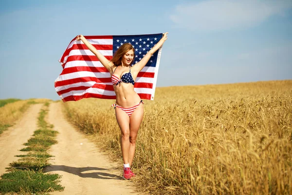 Mujer sexy en bikini sexy bandera americana en un campo de trigo —  Fotos de Stock