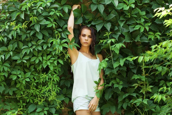 Linda morena em uma blusa turquesa posando contra um verde — Fotografia de Stock