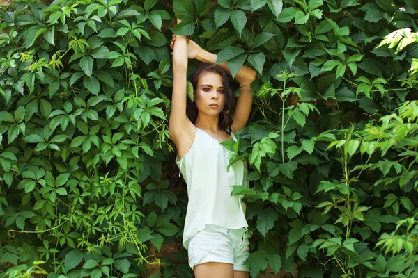 Linda morena em uma blusa turquesa posando contra um verde — Fotografia de Stock