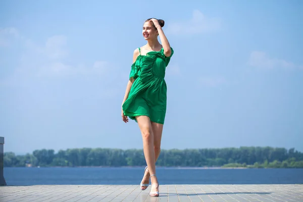 Молодая красивая женщина в зеленом платье ходить по летней улице — стоковое фото