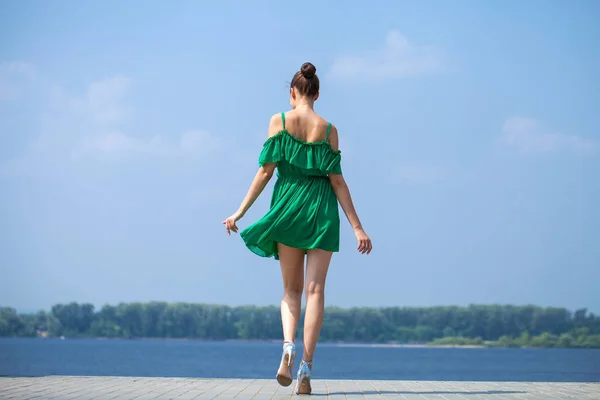 Jovem linda menina morena em vestido verde caminha ao longo do emb — Fotografia de Stock