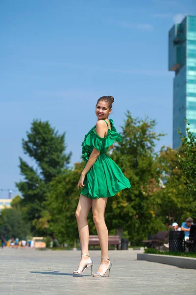 Young beautiful brunette girl in green dress walks along the emb — Stock Photo, Image