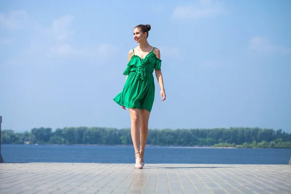 Young beautiful brunette girl in green dress walks along the emb — Stock Photo, Image