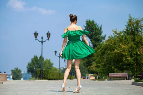 Young beautiful brunette girl in green dress walks along the emb — Stock Photo, Image