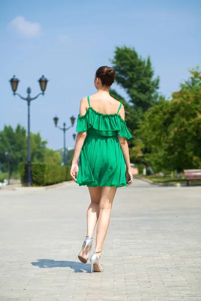 Joven chica morena hermosa en vestido verde camina a lo largo del emb —  Fotos de Stock