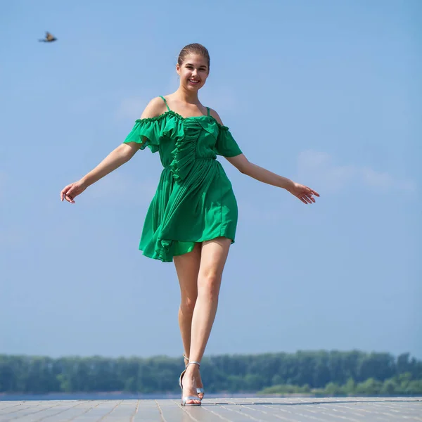 Young beautiful woman in green dress walking on the summer stree — Stock Photo, Image