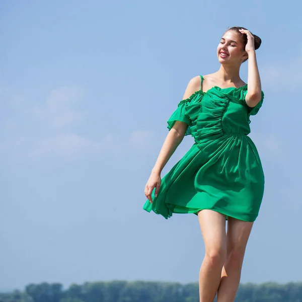年轻的美丽的女人在绿色的礼服走在夏天的树 — 图库照片