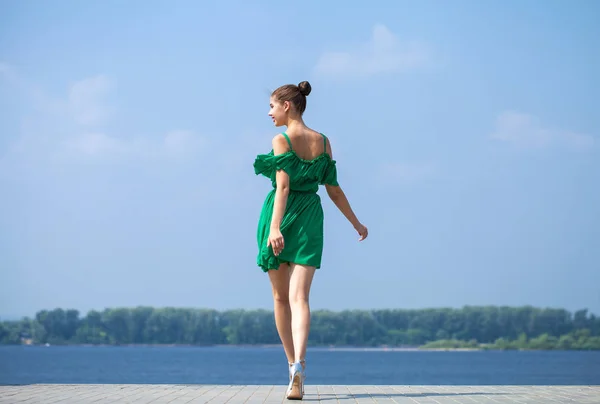 Jovem linda menina morena em vestido verde caminha ao longo do emb — Fotografia de Stock