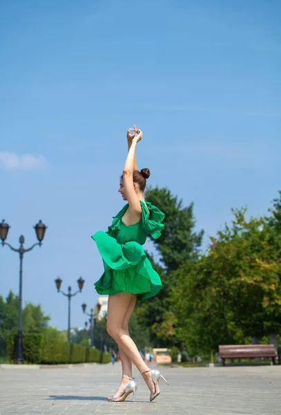 Fiatal, gyönyörű barna lány zöld ruhában sétál az emb — Stock Fotó