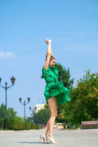 Jovem mulher bonita em vestido verde andando sobre a árvore de verão — Fotografia de Stock