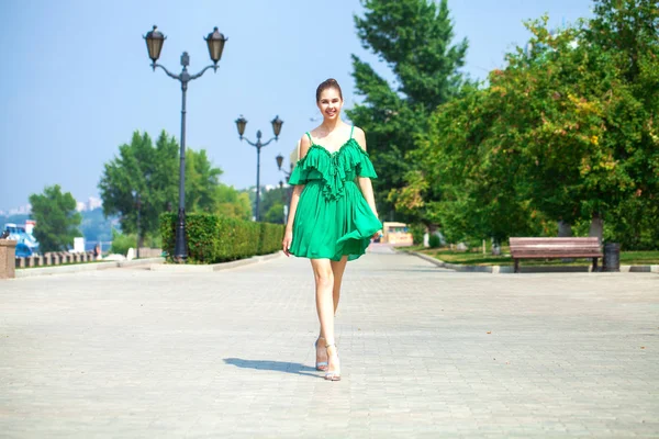 年轻的美丽的女人在绿色的礼服走在夏天的树 — 图库照片