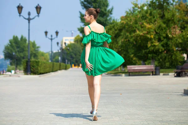 Joven chica morena hermosa en vestido verde camina a lo largo del emb —  Fotos de Stock