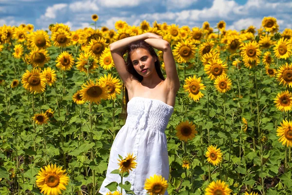 Retrato de una joven hermosa en un campo de girasoles — Foto de Stock