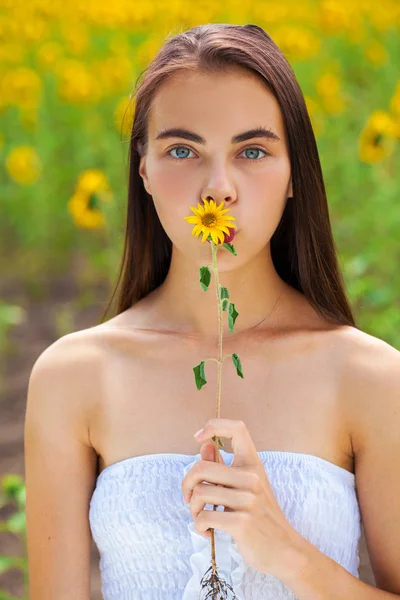 Retrato de una joven hermosa en un campo de girasoles — Foto de Stock