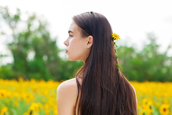 Retrato de una joven hermosa en un campo de girasoles — Foto de Stock