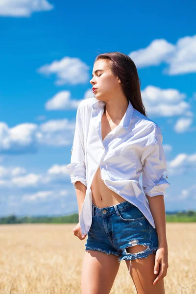 Jeune femme brune en chemise blanche et short en jean bleu — Photo