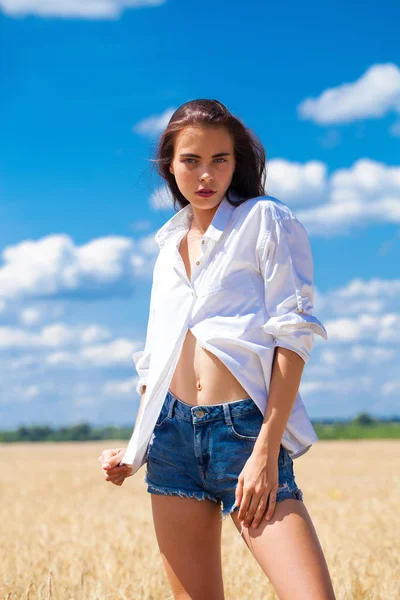 Jovem morena de camisa branca e calções jeans azuis — Fotografia de Stock