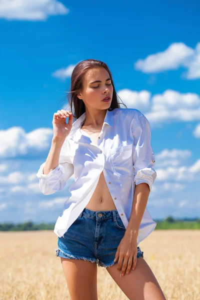 Young brunette woman in white shirt and blue jeans shorts — Stock Photo, Image