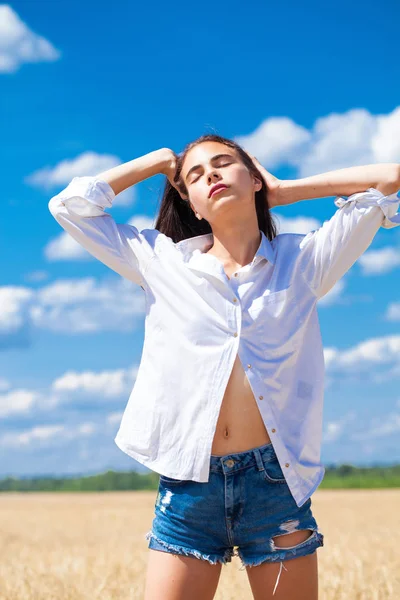 Mujer morena joven en camisa blanca y pantalones vaqueros azules —  Fotos de Stock