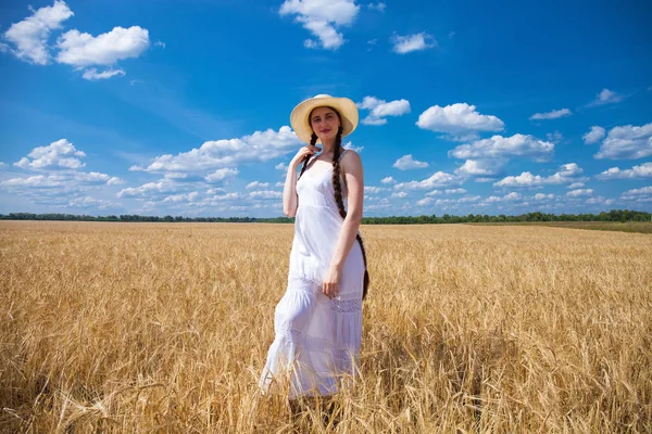 Счастливая брюнетка в белом платье и соломенной шляпе, ходящая в джинсах — стоковое фото