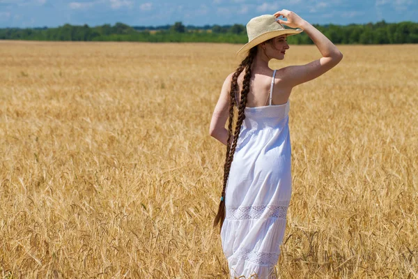 Beyaz elbiseli genç kadın bir whea mavi gökyüzüne karşı poz
