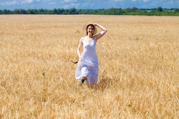 Felice donna bruna in abito bianco e cappello di paglia a piedi in un w — Foto Stock