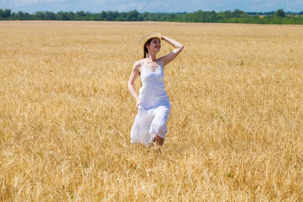 年轻的黑发女人在白色礼服走在麦田里 — 图库照片