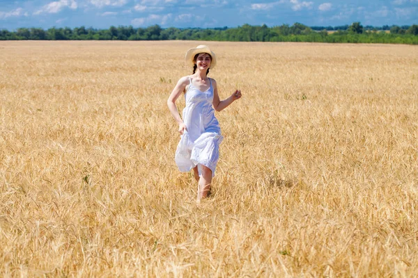 Happy brunette woman in white dress and straw hat walking in a w — Stock Photo, Image