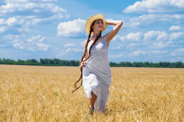Молодая брюнетка в белом платье ходит по пшеничному полю — стоковое фото