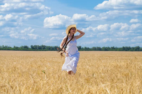 Young brunette woman in white dress walking in a wheat field — Stock Photo, Image