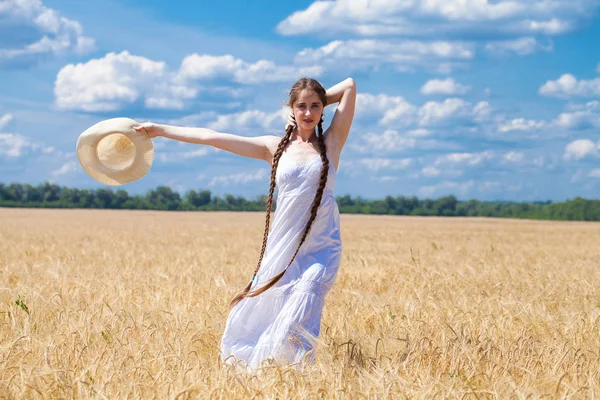 Glückliche brünette Frau in weißem Kleid und Strohhut, die in einem W — Stockfoto