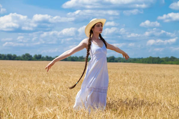 Beyaz elbiseli genç esmer kadın bir buğday tarlasında yürüyor