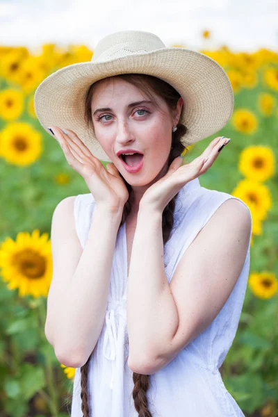 Porträtt av en ung vacker flicka i ett fält av solrosor — Stockfoto