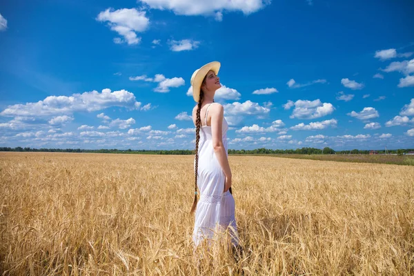 Happy brunette woman in white dress and straw hat walking in a w Royalty Free Stock Photos